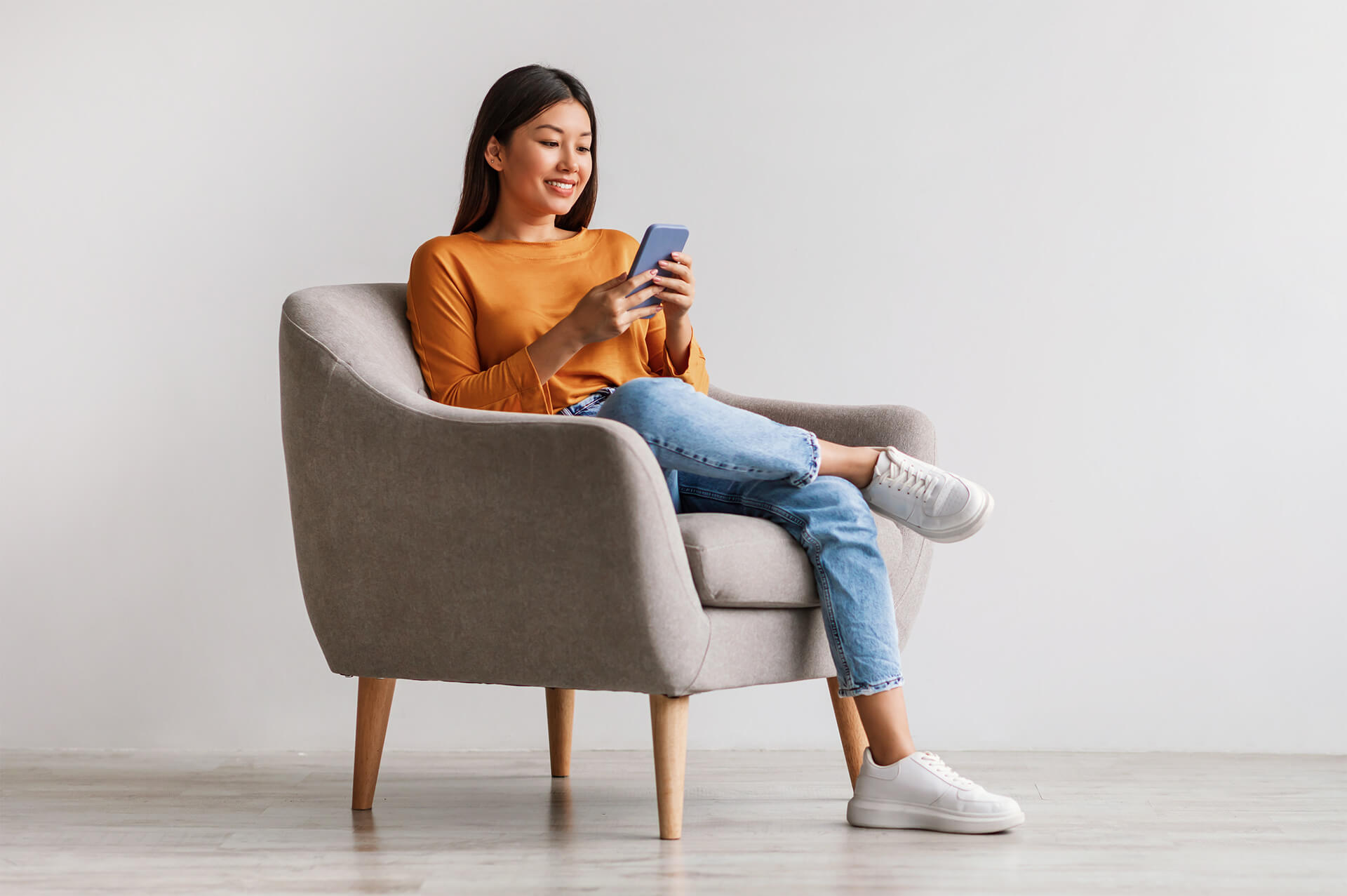 Femme assise en train de regarder son smartphone, illustrant les compétences comportementales (soft skills) clés à développer en 2025.